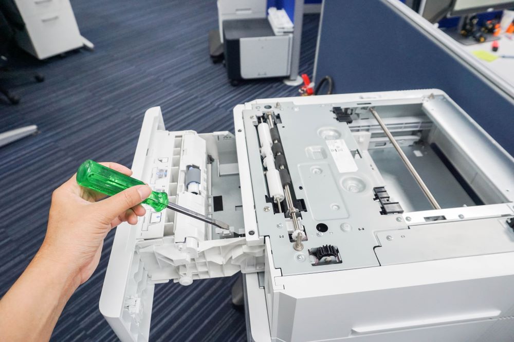 Close up of a technician taking a screwdriver to a copier signifying Xerox repair.