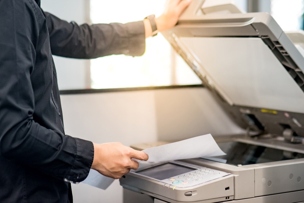 Employee standing at an MFP representing Managed Print Services