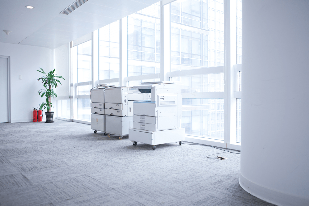 Two large copiers in a modern office setting symbolizing copier service maintenance agreements
